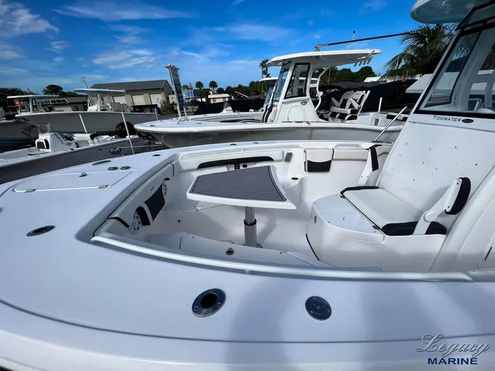  Yacht Photos Pics 2024 Tidewater 272 CC Adventure boat interior with seating and table, under clear blue sky.