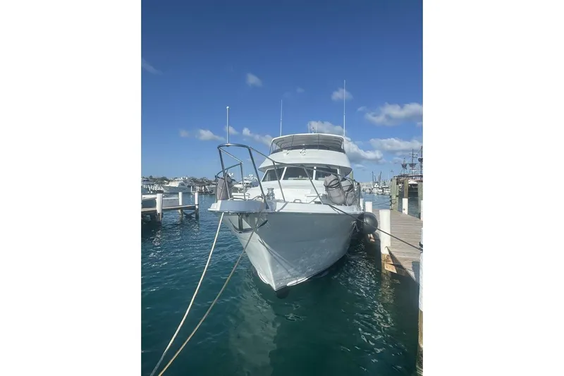 Island Dancer Yacht Photos Pics Hatteras 75 Sport Deck Motor Yacht 2000 docked in a marina under clear blue skies.