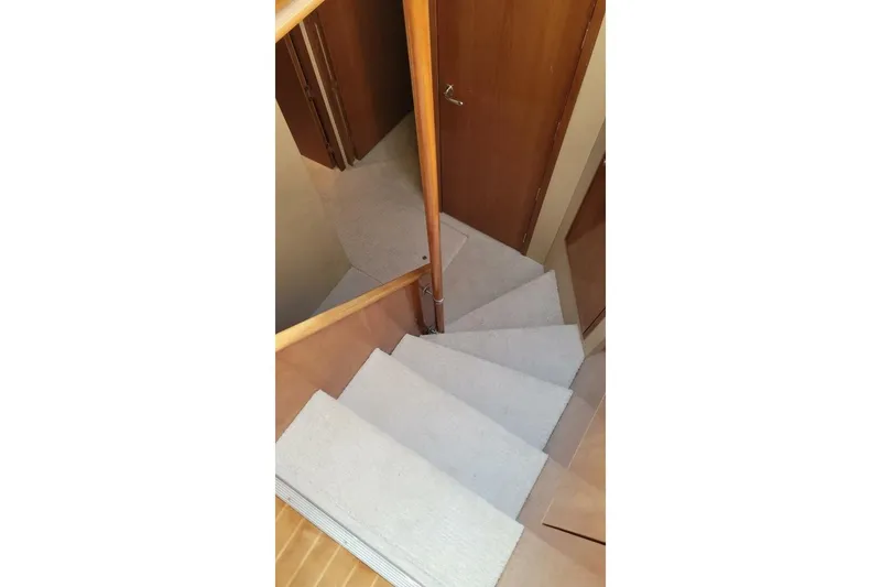 Island Dancer Yacht Photos Pics Staircase inside 2000 Hatteras 75 Sport Deck Motor Yacht, featuring wooden railings and carpeted steps.