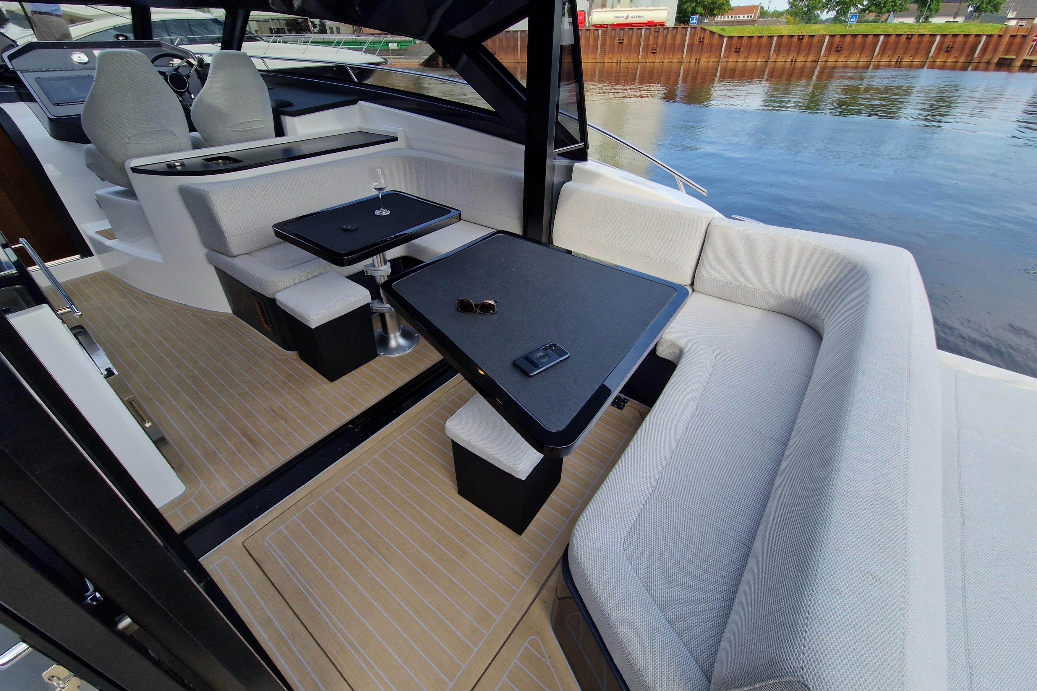 Luxurious 2023 Focus Power 44 yacht interior with elegant seating and tables by the water.