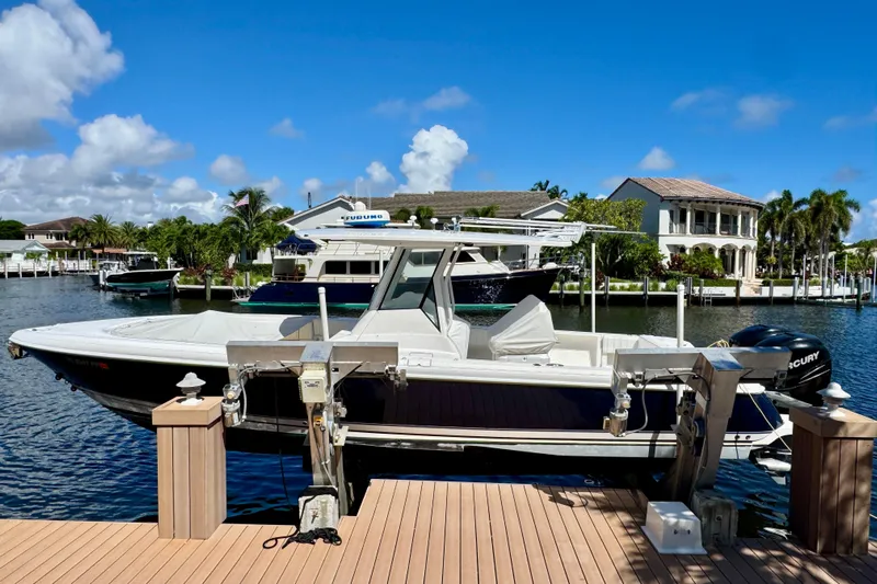  Yacht Photos Pics 2014 Intrepid 327 Center Console boat docked by waterfront homes under blue sky.