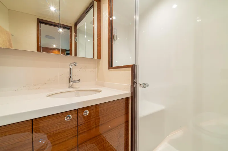 Yacht Photos Pics Luxurious bathroom in 2022 Jarrett Bay Flybridge Express yacht, featuring sleek wood cabinetry and modern fixtures.