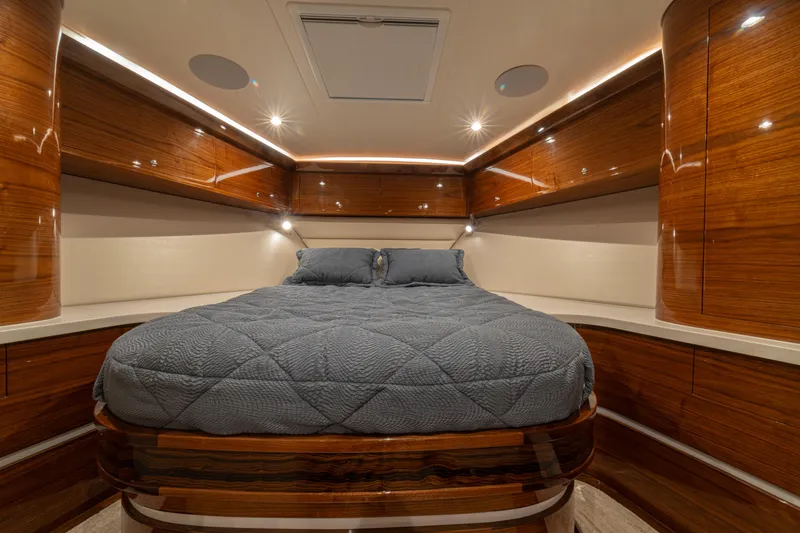  Yacht Photos Pics Luxurious 2022 Jarrett Bay Flybridge Express cabin with elegant wood finish and cozy bedding.