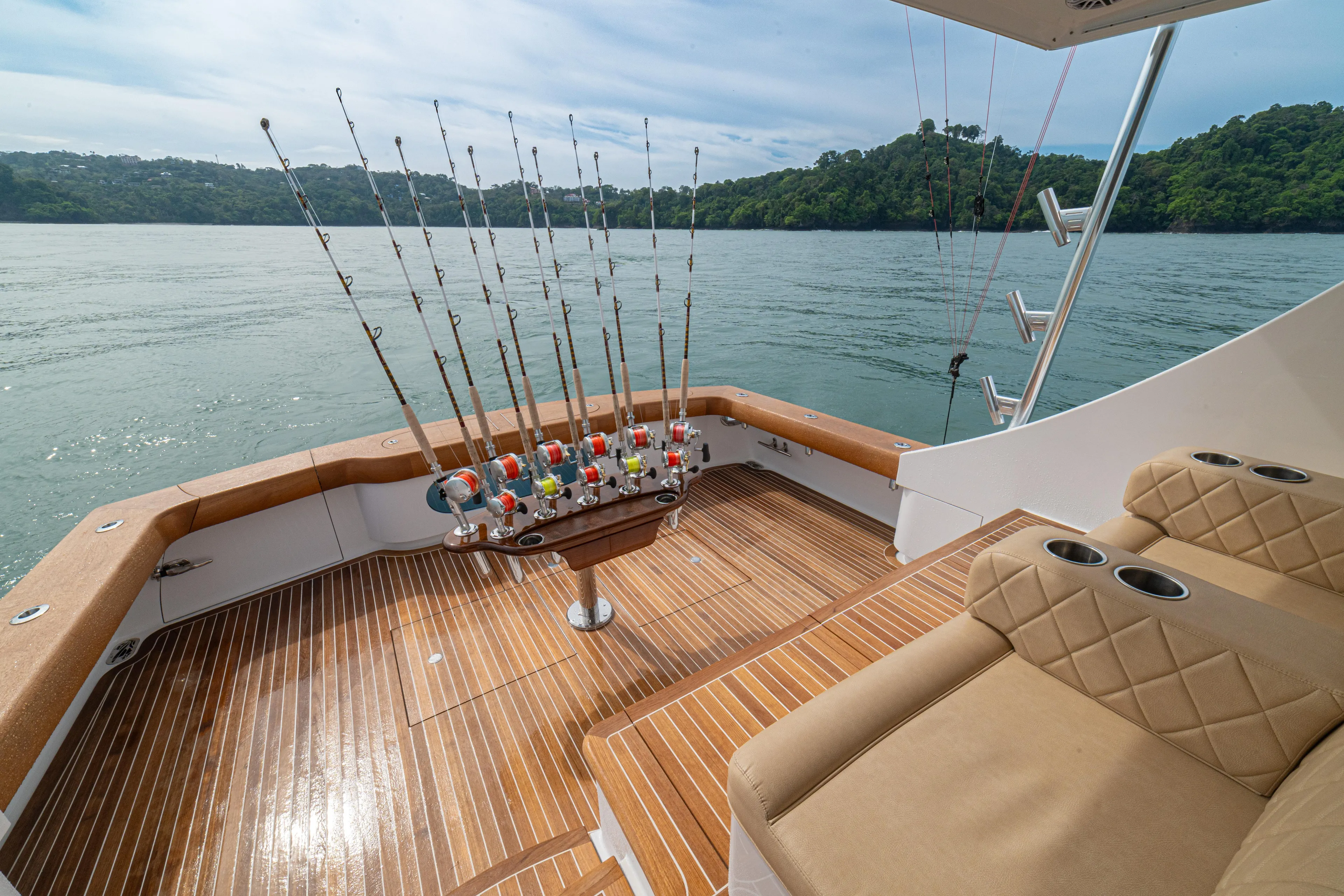  Yacht Photos Pics 2022 Jarrett Bay Flybridge Express with fishing rods on deck, overlooking serene waters and lush greenery.