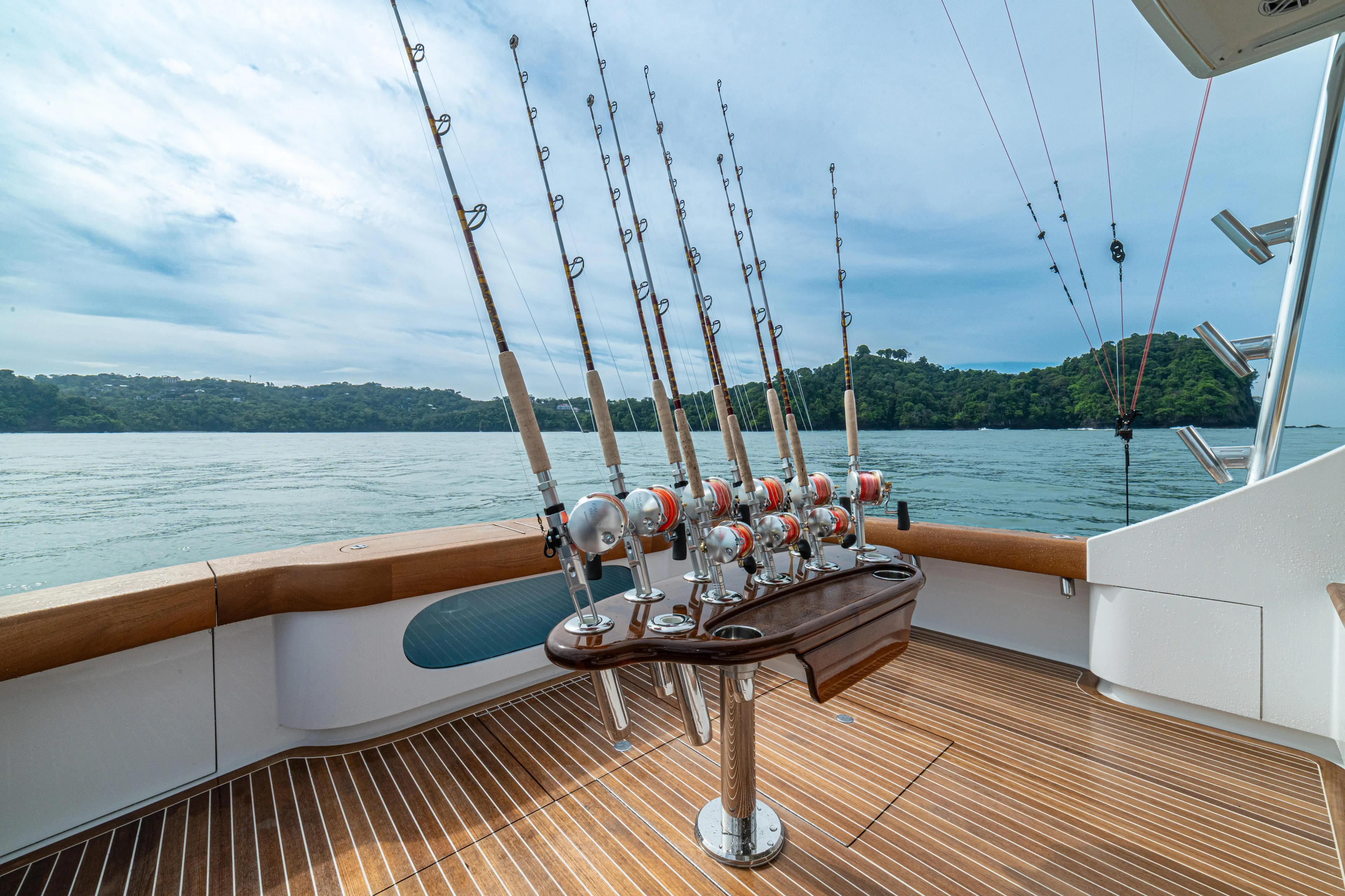  Yacht Photos Pics 2022 Jarrett Bay Flybridge Express with fishing rods on deck, overlooking serene waters.