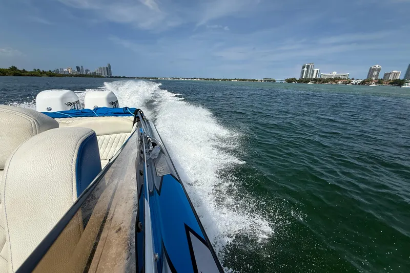  Yacht Photos Pics Velocity 290sc 2021 speedboat cruising on a sunny day with city skyline in background.