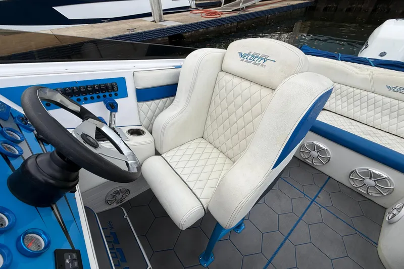  Yacht Photos Pics Captain's seat and dashboard of a 2021 Velocity 290sc boat, featuring blue accents and controls.