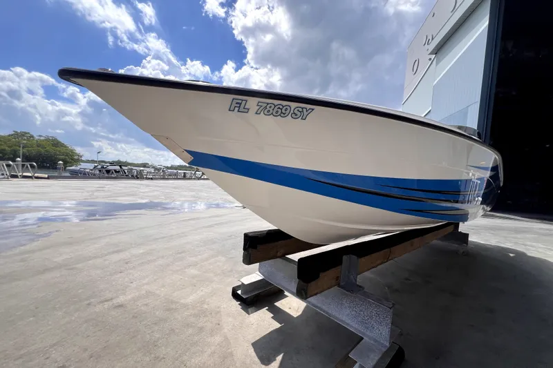  Yacht Photos Pics 2021 Velocity 290sc boat on stand, blue stripes, sunny day, marina background.