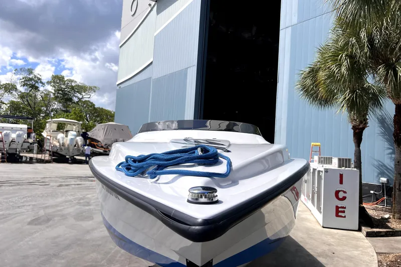  Yacht Photos Pics 2021 Velocity 290sc boat docked near a blue building with palm trees.