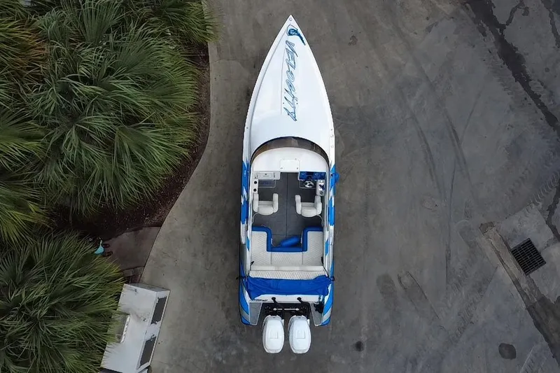  Yacht Photos Pics Aerial view of 2021 Velocity 290sc speedboat with dual engines, parked near lush greenery.