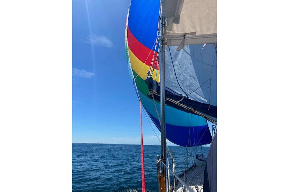 Colorful spinnaker sail on 1995 Rival 36 yacht against clear blue sky and ocean.