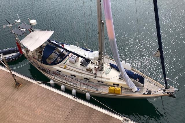 Sailboat docked at marina, Rival 36 model, 1995, with blue canopy and wooden deck.