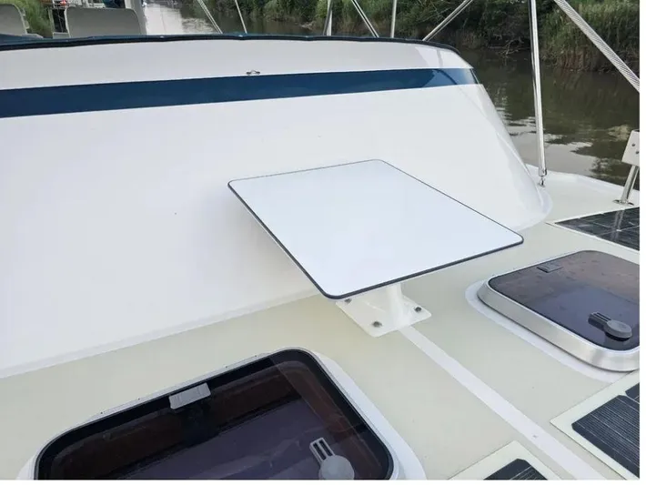 Carmella Yacht Photos Pics 2019 Kadey-Krogen 44AE yacht deck with table and hatches, docked by a river.