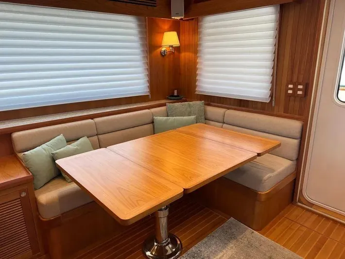 Carmella Yacht Photos Pics 2019 Kadey-Krogen 44AE yacht interior with wooden dining table and cushioned seating.