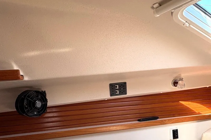 Sea Fever IV Yacht Photos Pics Interior of a 2022 Catalina 355 sailboat, featuring a fan, outlet, and wooden paneling.