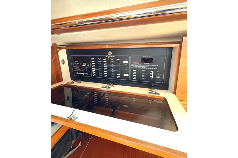 Sea Fever IV Yacht Photos Pics Electrical panel inside 2022 Catalina 355 yacht, featuring control switches and wooden cabinetry.