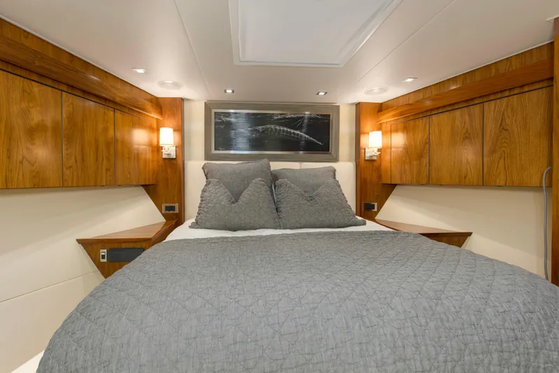 Touche Yacht Photos Pics Luxurious bedroom interior of 2016 Viking 92 Enclosed Bridge yacht with wood accents and cozy bedding.