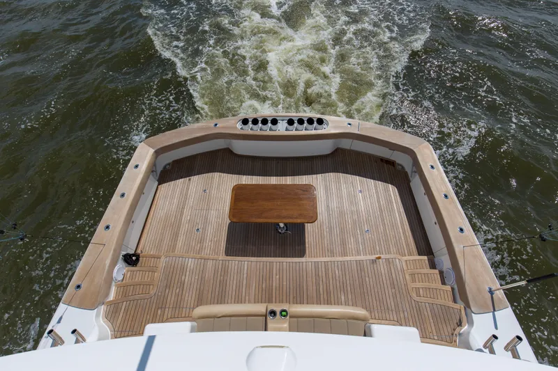 Touche Yacht Photos Pics 2016 Viking 92 Enclosed Bridge yacht deck with wooden flooring and table, cruising on water.