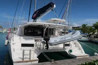2020 Leopard 45 catamaran docked with inflatable boat, tropical marina background.