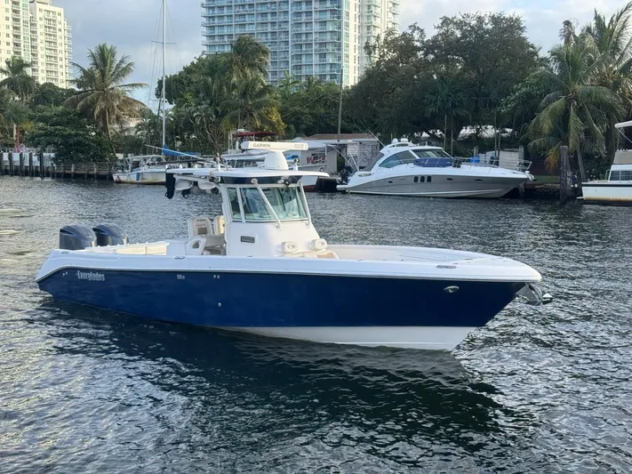  Yacht Photos Pics 2011 Everglades 320 Center Console boat on water, surrounded by palm trees and buildings.