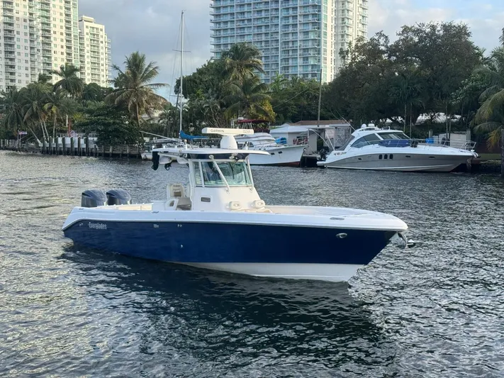  Yacht Photos Pics 2011 Everglades 320 Center Console boat on water, with cityscape and palm trees in background.