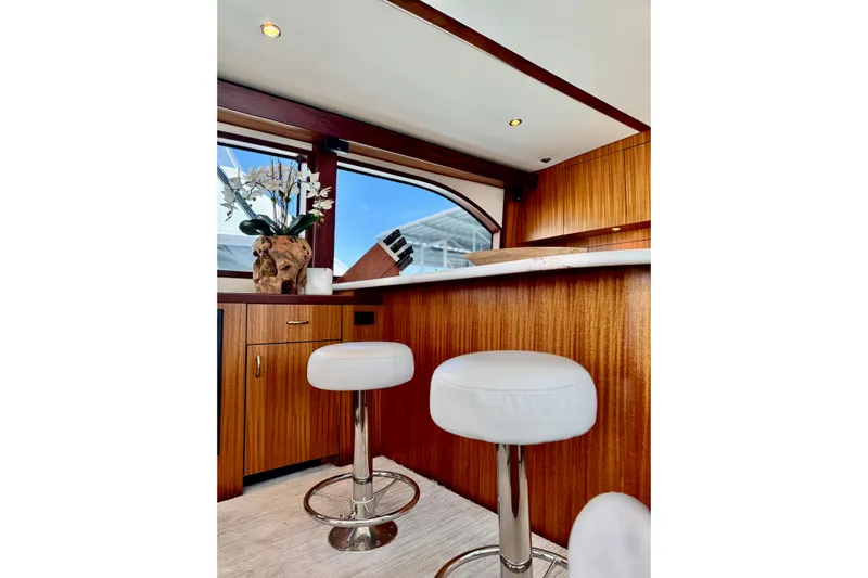 Yacht Photos Pics Luxurious interior of 2013 Hatteras GT60 yacht with elegant bar stools and wood finish.