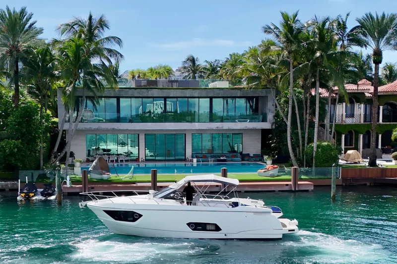  Yacht Photos Pics Luxury yacht Absolute 40 cruising near modern waterfront mansion, surrounded by palm trees.