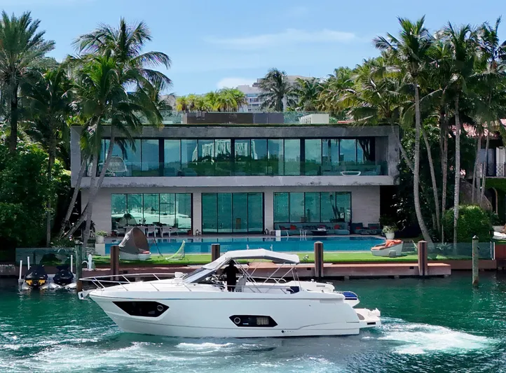 Yacht Photos Pics Luxury yacht Absolute 40 cruising near modern waterfront mansion, surrounded by palm trees.