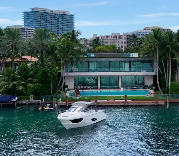  Yacht Photos Pics Luxurious Absolute 40 yacht near modern waterfront mansion, surrounded by palm trees and cityscape.