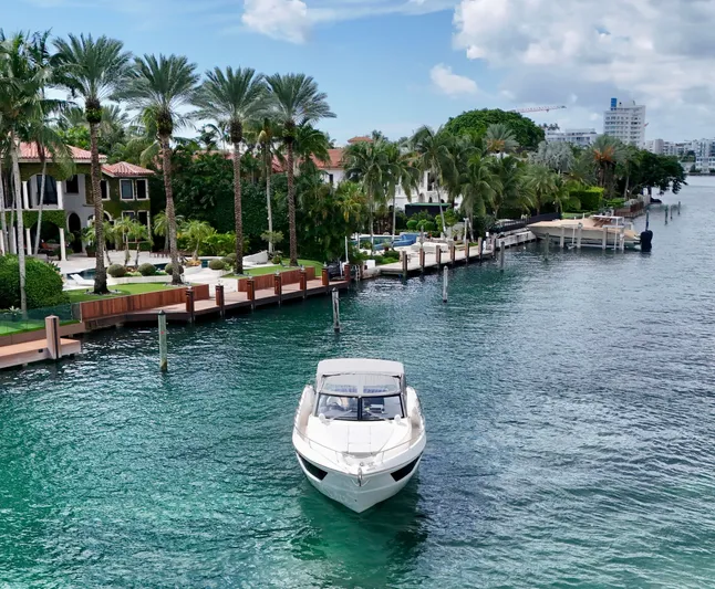  Yacht Photos Pics Luxury yacht Absolute 40 cruising near waterfront homes, surrounded by palm trees and clear blue water.