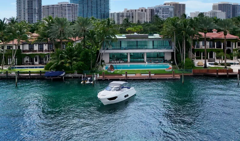  Yacht Photos Pics Luxury yacht Absolute 40, 2014 model, cruising near waterfront mansion with palm trees and modern architecture.