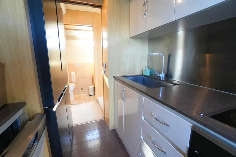 Hubo Yacht Photos Pics Compact kitchen area on a 2016 Azimut 84 yacht, featuring modern cabinetry and stainless steel sink.