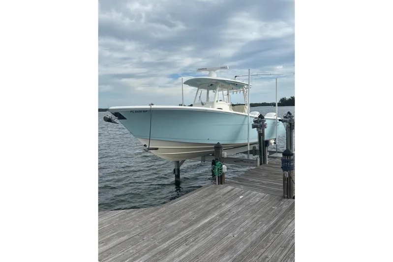  Yacht Photos Pics 2018 Cobia 320 Center Console boat docked on a lift by the water.
