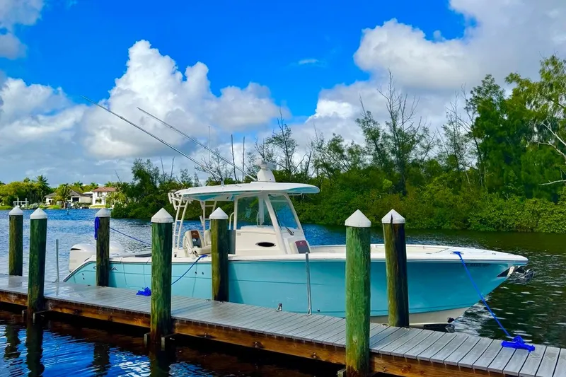  Yacht Photos Pics 2018 Cobia 320 Center Console boat docked by a scenic waterfront.