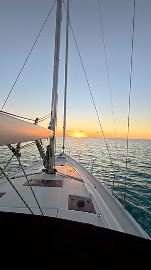 Genesis Yacht Photos Pics Jeanneau 54 sailboat at sunset, 2021 model, cruising on calm ocean waters.