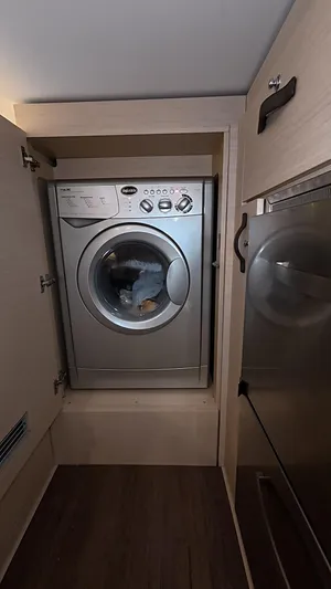 Genesis Yacht Photos Pics Washing machine inside Jeanneau 54 yacht, 2021 model, with wooden cabinetry.