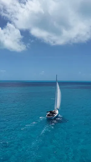 Genesis Yacht Photos Pics Jeanneau 54 sailboat cruising on clear blue ocean under a partly cloudy sky.