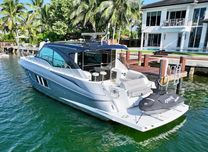 Insieme Yacht Photos Pics 2018 Cruisers Yachts 45 Cantius docked by a waterfront home, surrounded by palm trees.