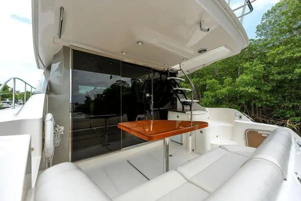No Pods - V-drive Yacht Photos Pics 2015 Sea Ray 510 Fly yacht with outdoor seating and table, surrounded by lush greenery.