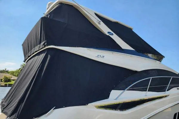 No Pods - V-drive Yacht Photos Pics 2015 Sea Ray 510 Fly yacht with black covers, docked under clear blue sky.