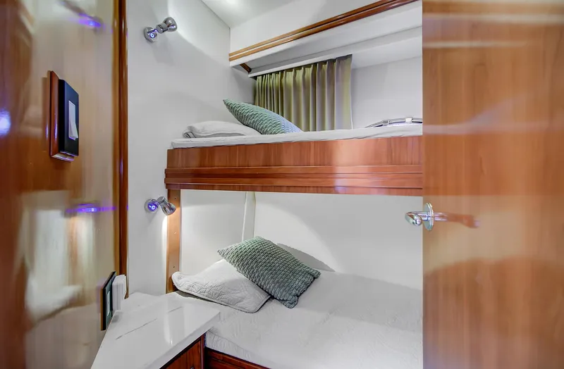 No Surrender Yacht Photos Pics Bunk beds in 2000 Carver 530 Voyager Pilothouse cabin with wooden accents and cozy lighting.