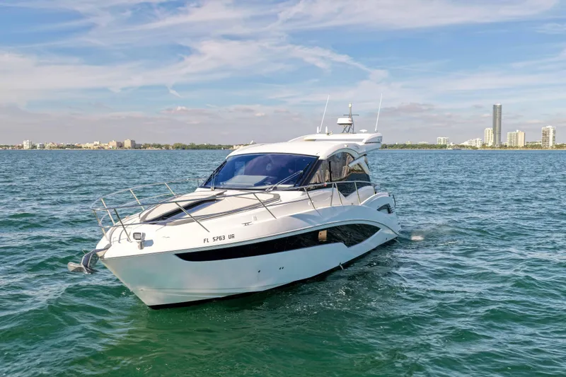  Yacht Photos Pics 2021 Galeon 425 HTS yacht cruising on open water with city skyline backdrop.