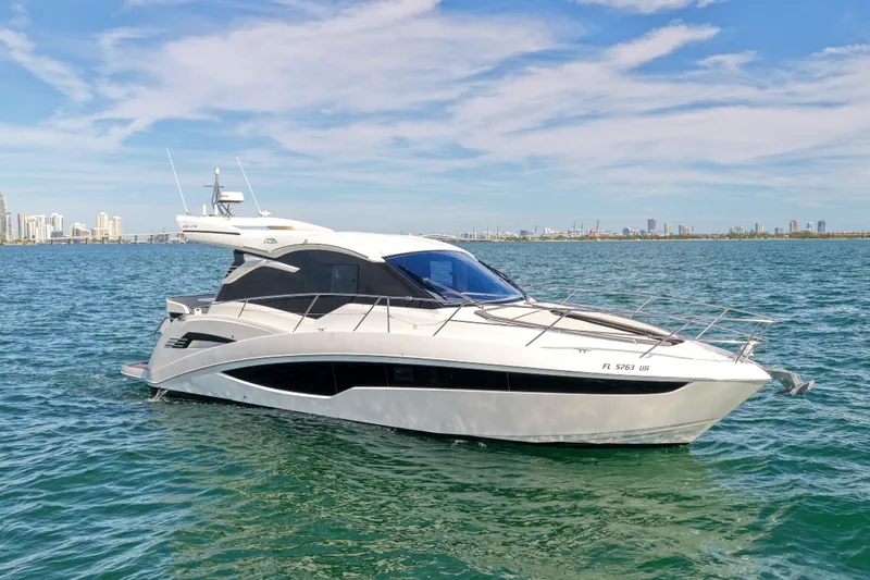  Yacht Photos Pics 2021 Galeon 425 HTS yacht cruising on open water with city skyline backdrop.