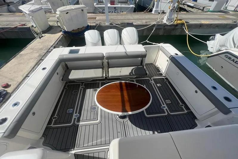 Yacht Photos Pics 2018 Pursuit OS 385 Offshore boat deck with seating and round table at marina.