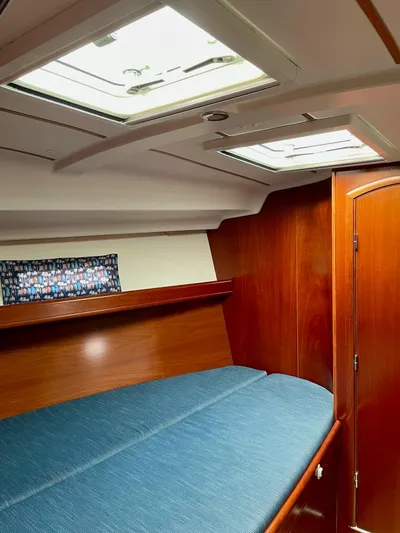 Oasis Yacht Photos Pics Interior cabin of 2004 Beneteau Oceanis 393 with wooden finish and blue bedding.