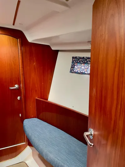 Oasis Yacht Photos Pics Interior cabin of 2004 Beneteau Oceanis 393 sailboat with wooden finish and blue cushioned seating.