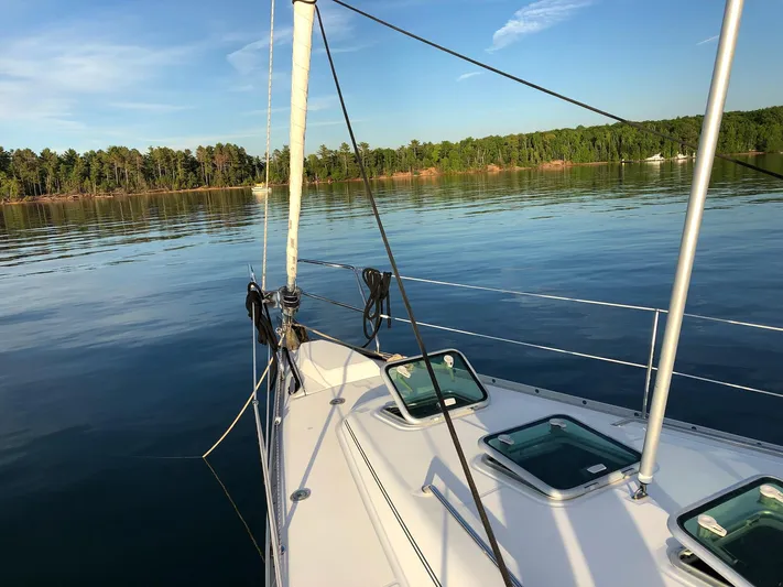 Oasis Yacht Photos Pics 2004 Beneteau Oceanis 393 sailboat on calm water with forested shoreline.