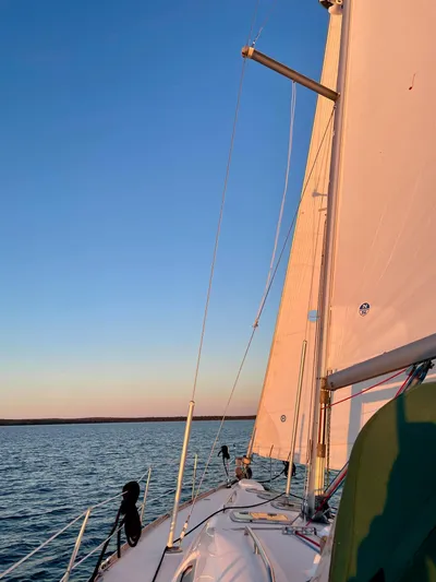 Oasis Yacht Photos Pics 2004 Beneteau Oceanis 393 sailing at sunset on calm waters.