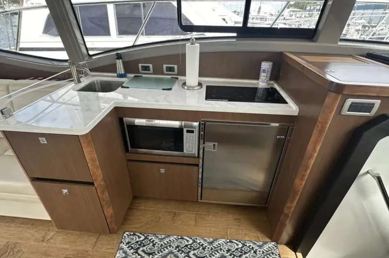 Logan Yacht Photos Pics Modern kitchen area in a 2018 Sea Ray Sundancer 400 yacht with appliances and wood cabinetry.