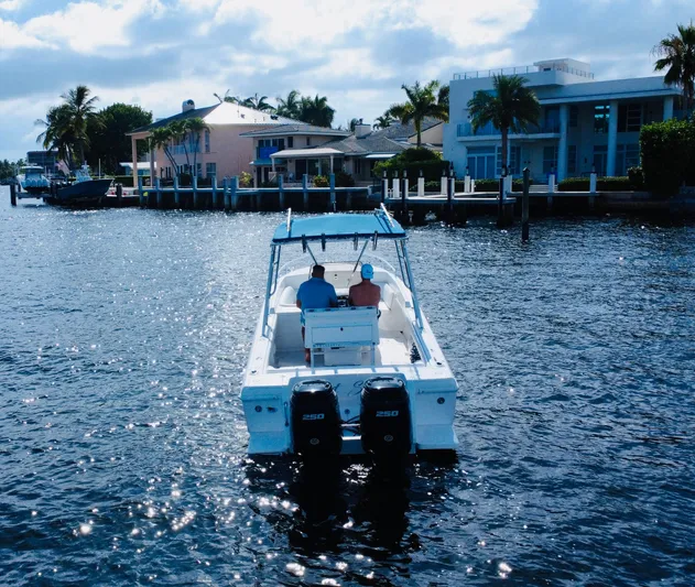  Yacht Photos Pics 2002 Intrepid 323 Cuddy boat cruising near waterfront homes under a partly cloudy sky.